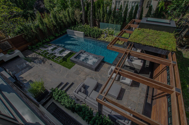 A landscaped backyard swimming pool and stone patio built by Pro-Land Landscape Construction.